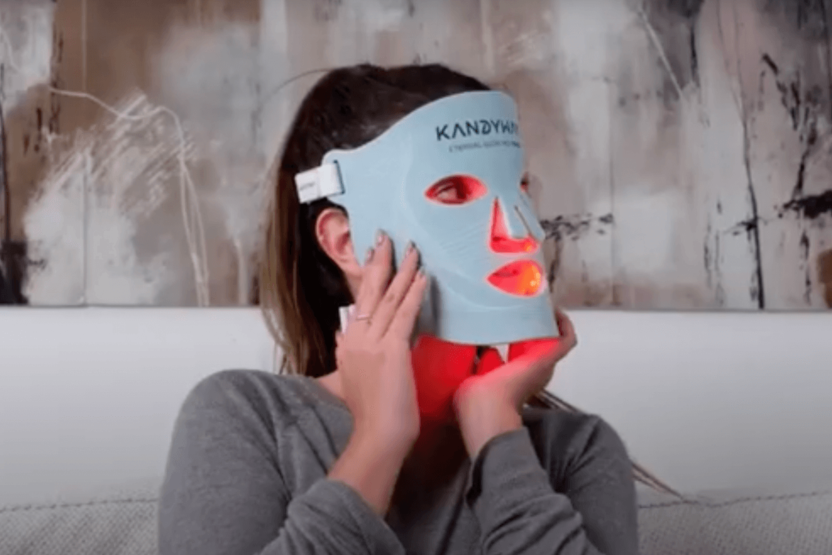 Woman using red light therapy mask.